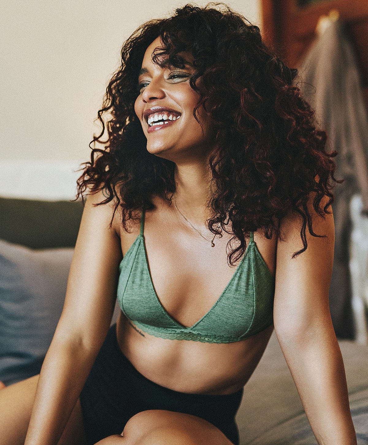 Smiling woman in green lingerie, joyful expression.