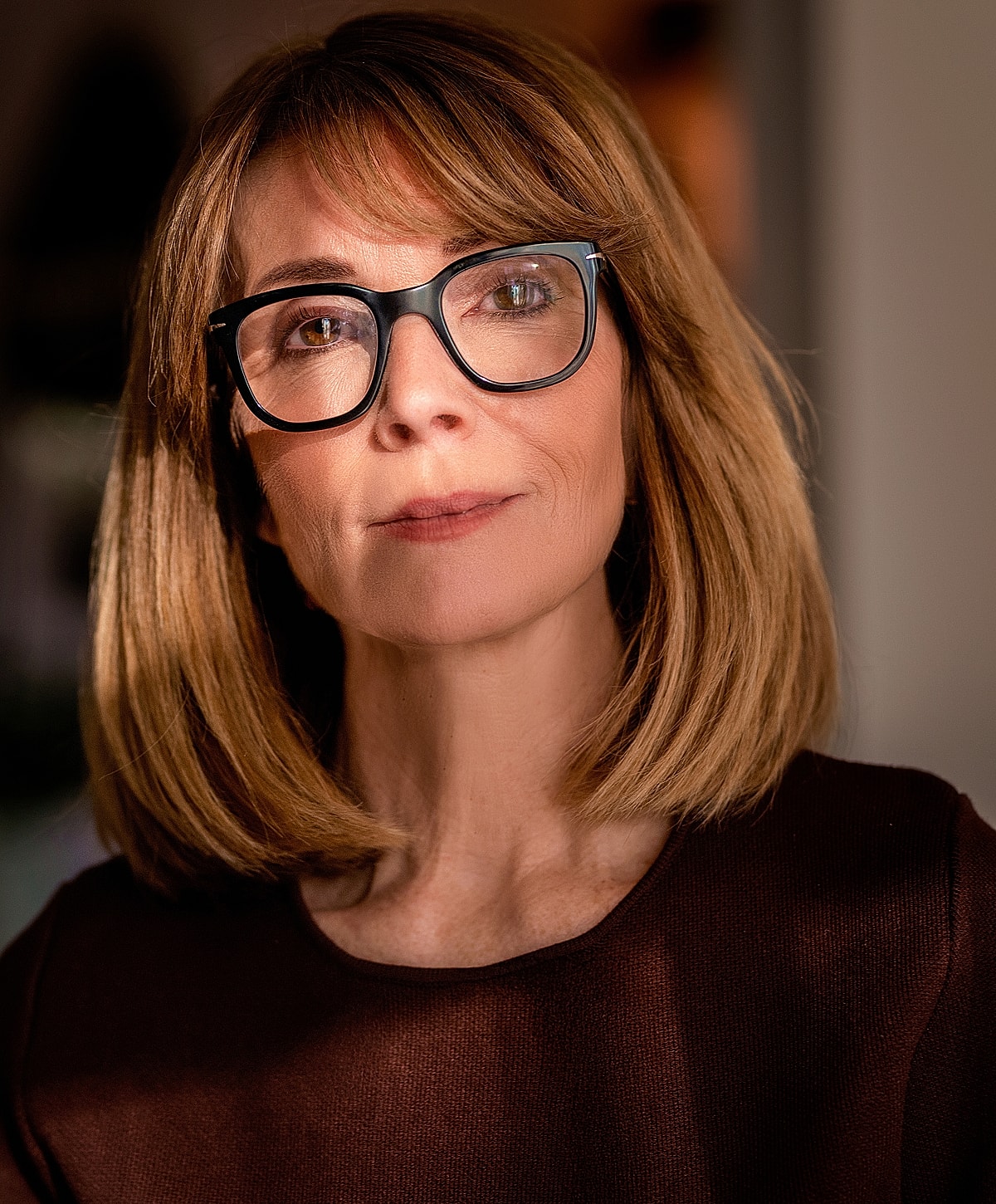 Woman with glasses and short hair, thoughtful expression.