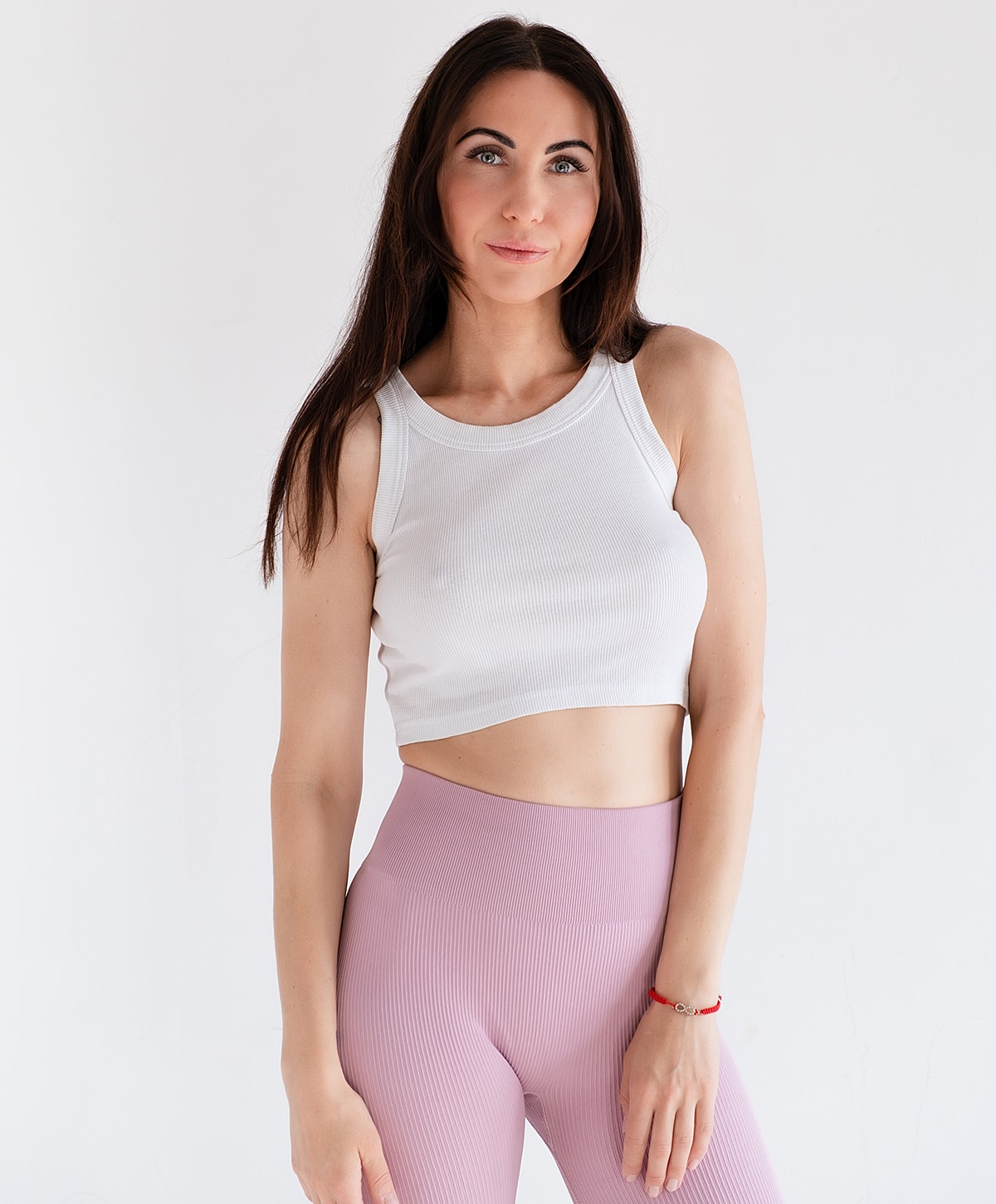 Woman in white crop top and pink leggings.