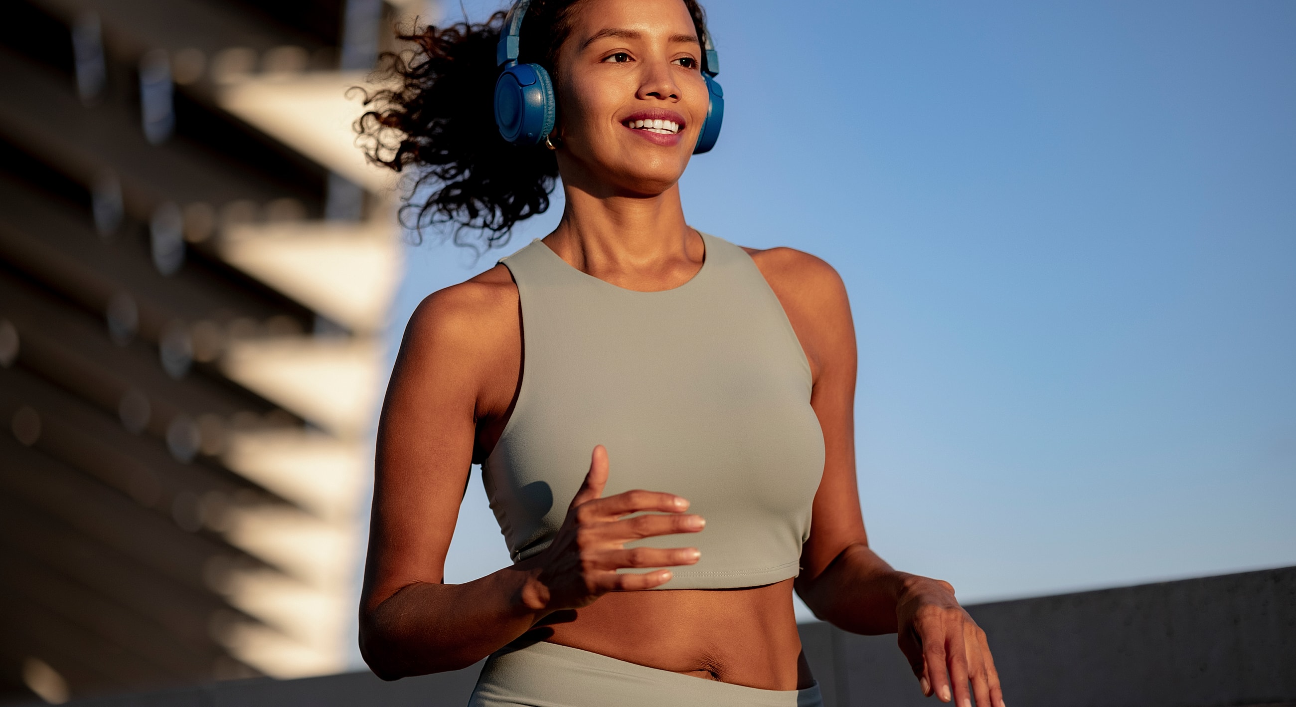 Woman jogging outdoors with headphones on.