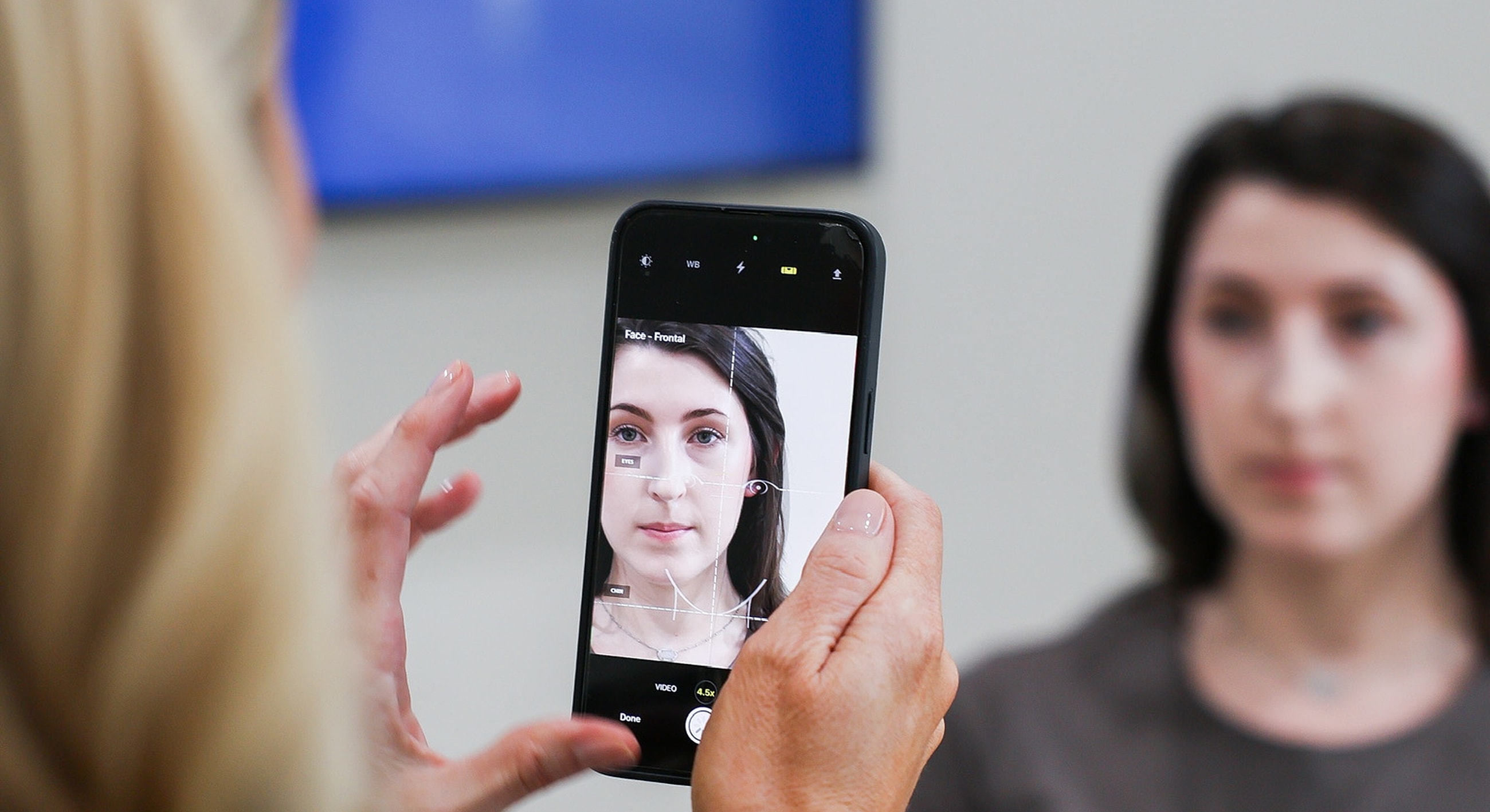Person taking a photo of a model's face.
