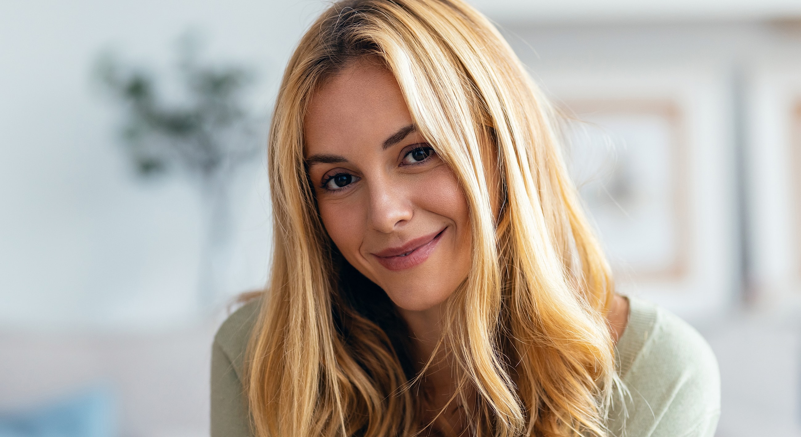 Smiling woman with long blonde hair indoors.